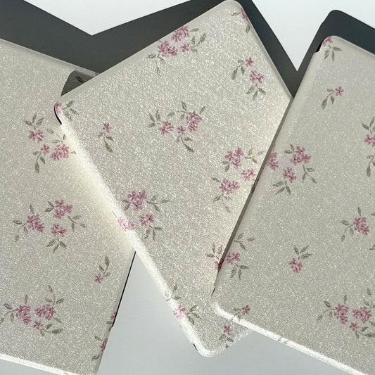 Three Blooming Kindle cases fanned together, pink blossoms and sage leaves on ivory