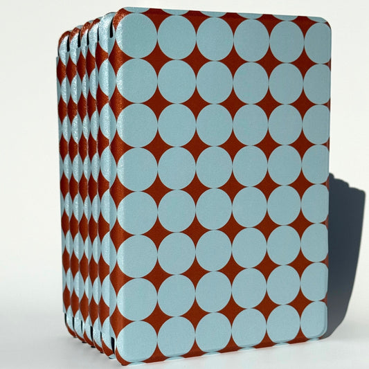 Blue polka dot Kindle cases fanned upright, copper shimmer glinting between soft blue dots