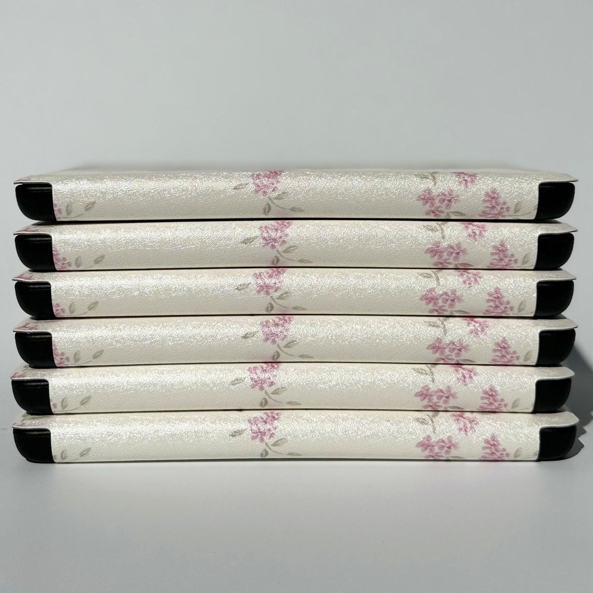Neat stack of six Blooming ditsy floral Kindle cases showing the pearly finish