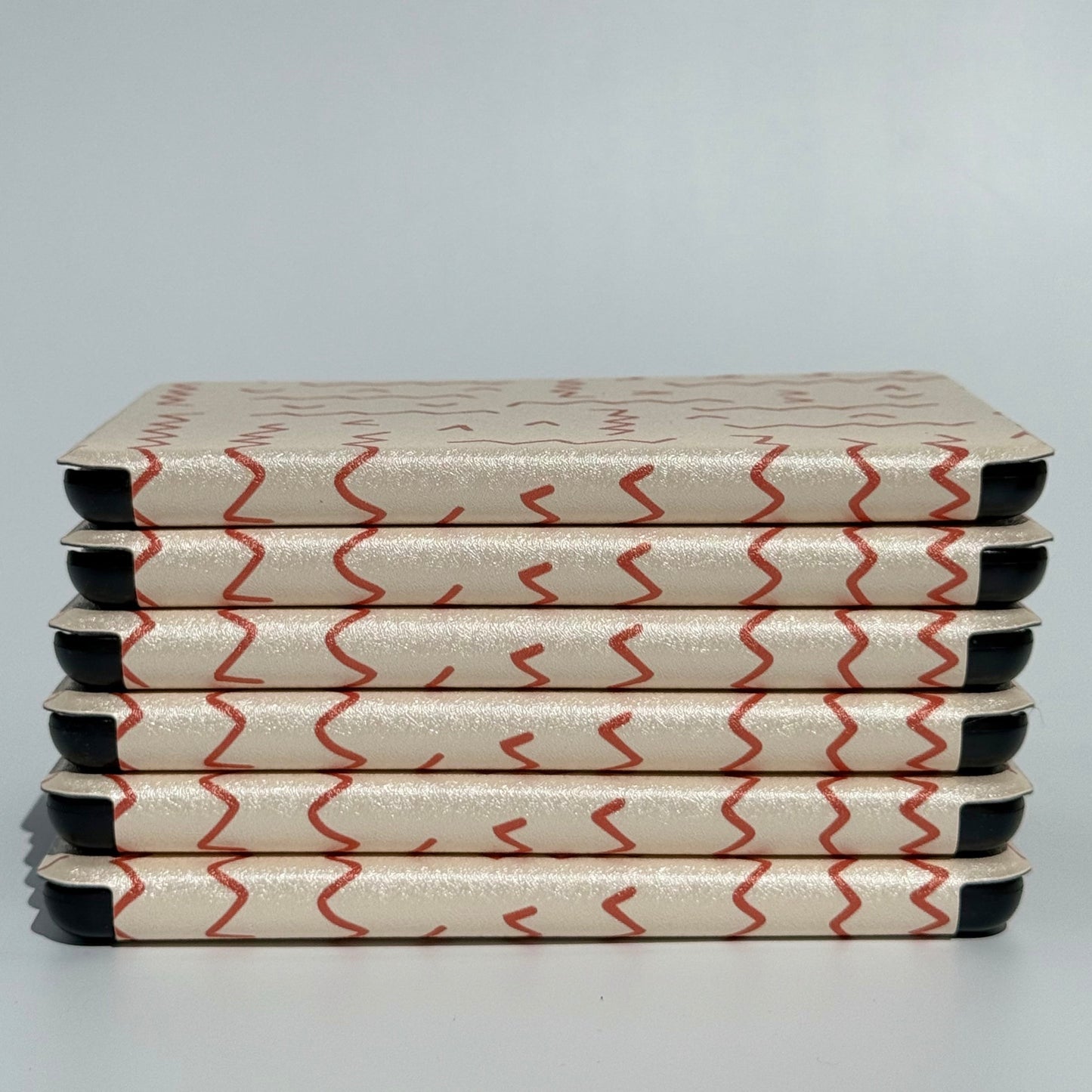 Between The Lines oatmeal and red squiggle Kindle cases stacked, Case Society Australia