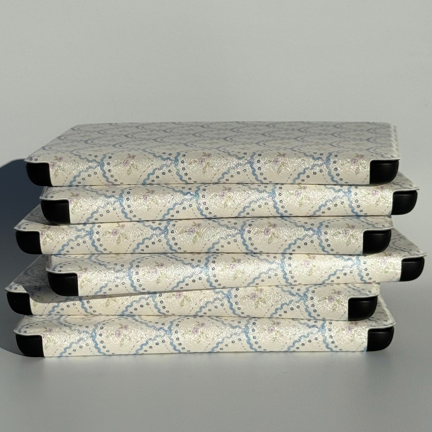 STACK OF WHITE KINDLE CASES WITH COTTAGE CORE PRINT