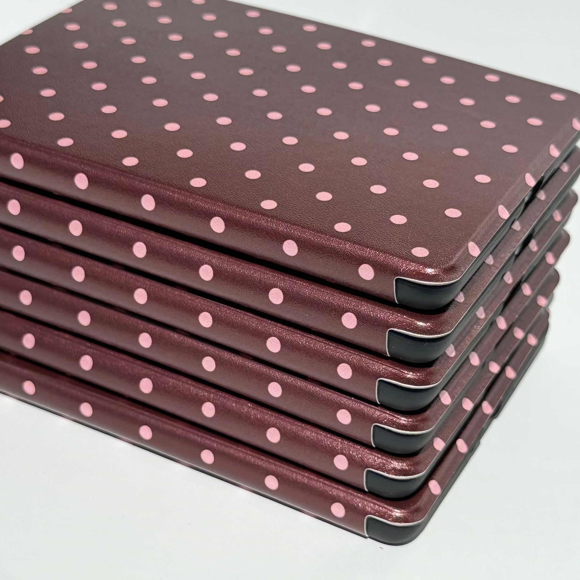 Stack of Cocoa Kiss Kobo cases, chocolate brown covers with soft pink polka dots and black corner bumpers