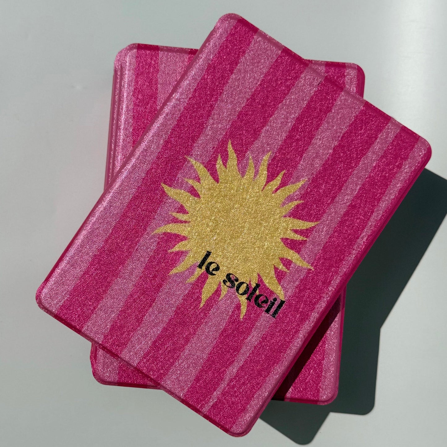 Front view of the Le Soleil Kindle case, raspberry pink stripes with a golden sun