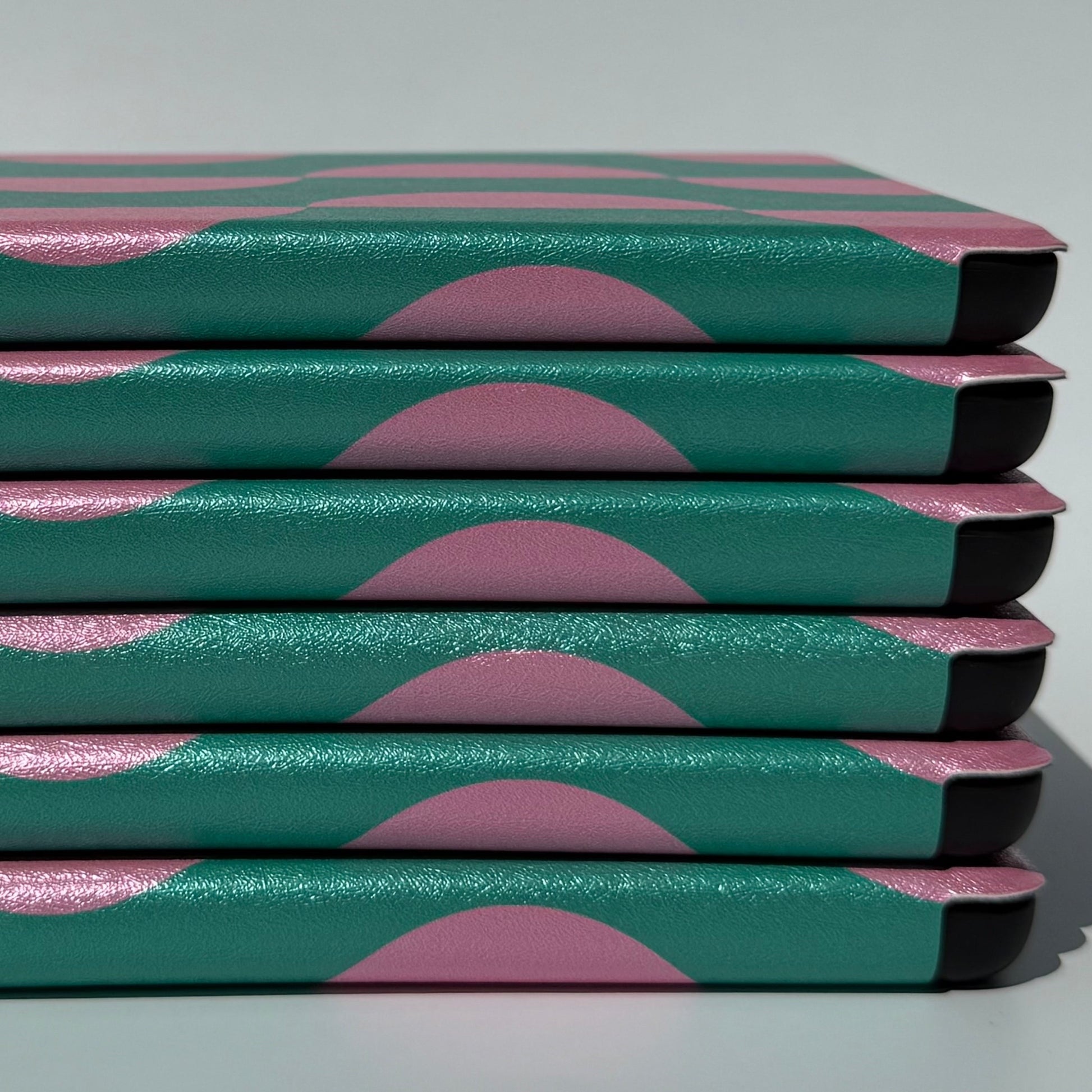 Close-up side stack of Pink Crescent green and pink Kindle cases