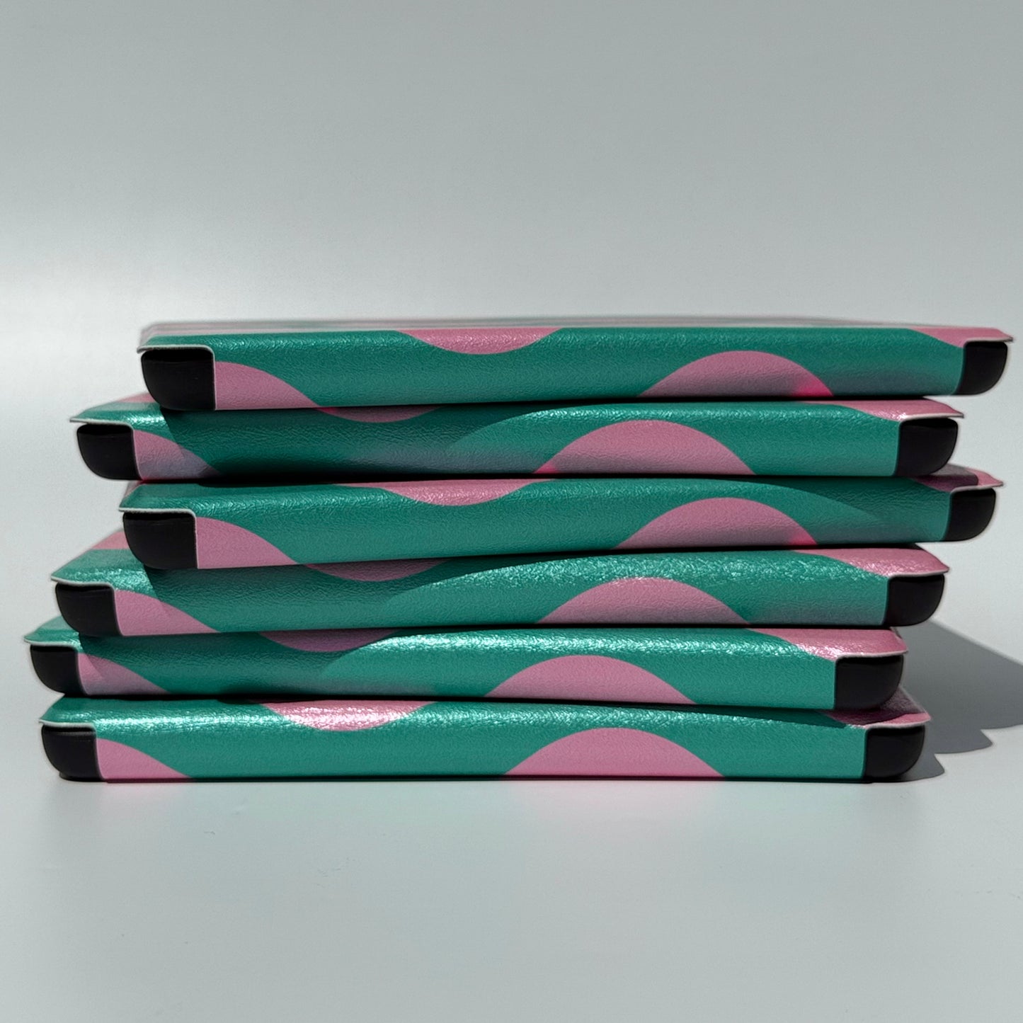 Side view of a messy stack of Case Society Pink Crescent Kindle Cases