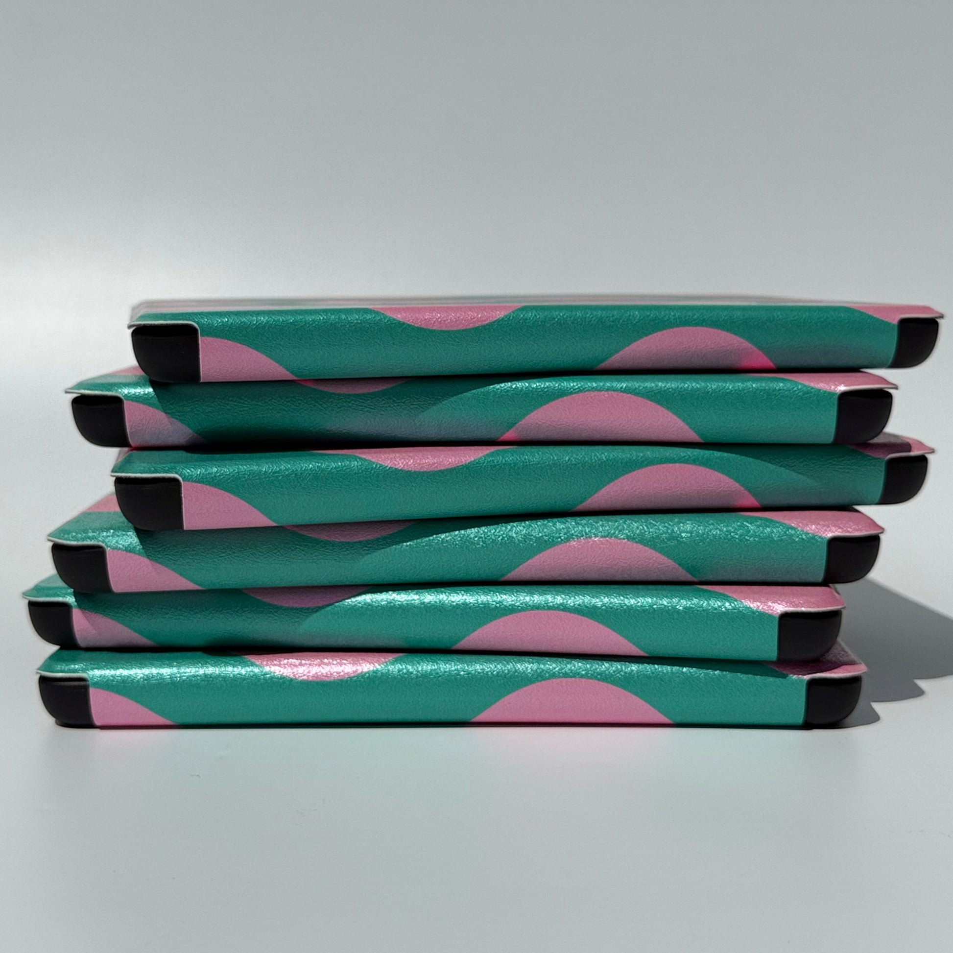 Side view of a messy stack of Case Society Pink Crescent Kindle Cases