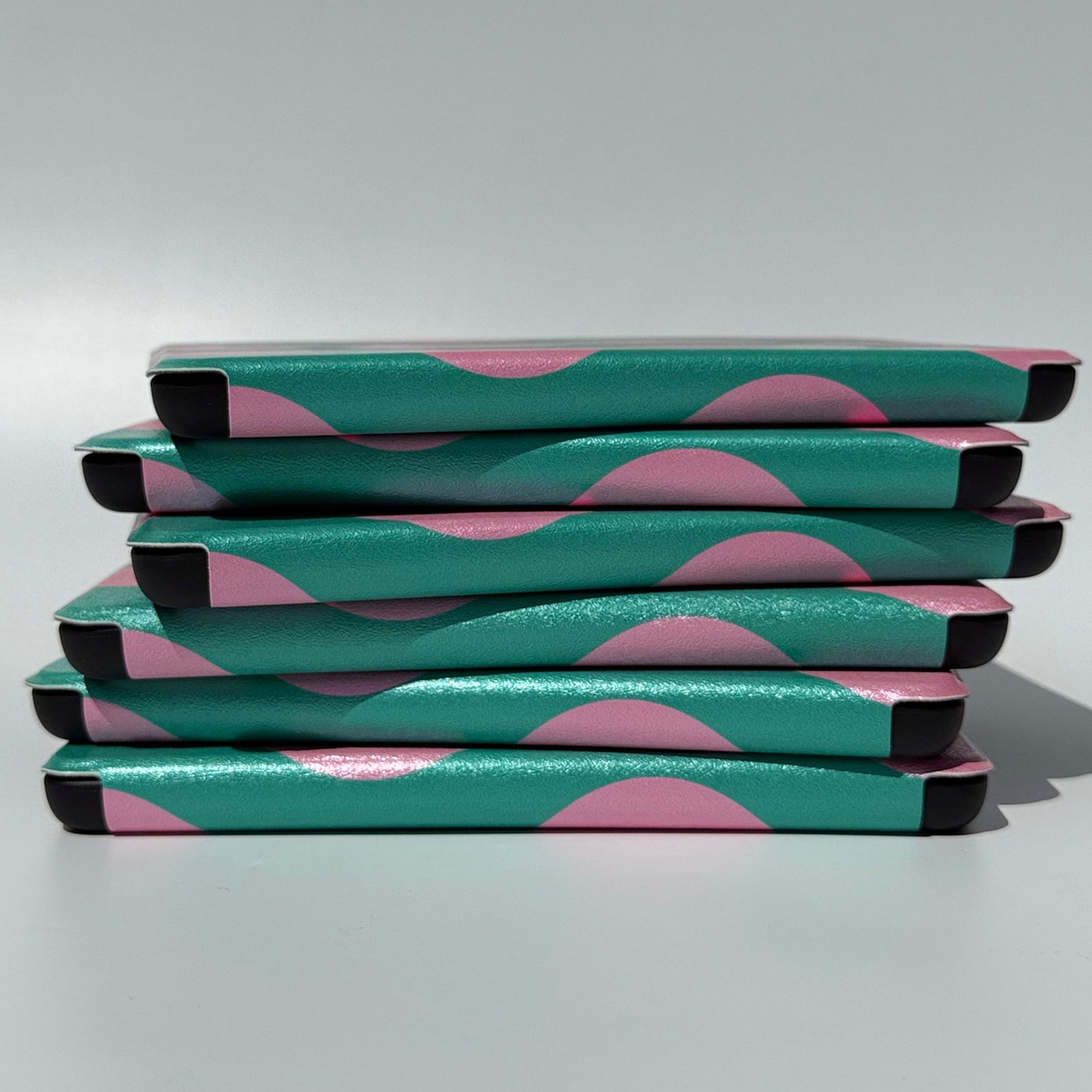 Side view of stacked Pink Crescent green and pink crescent Kindle cases