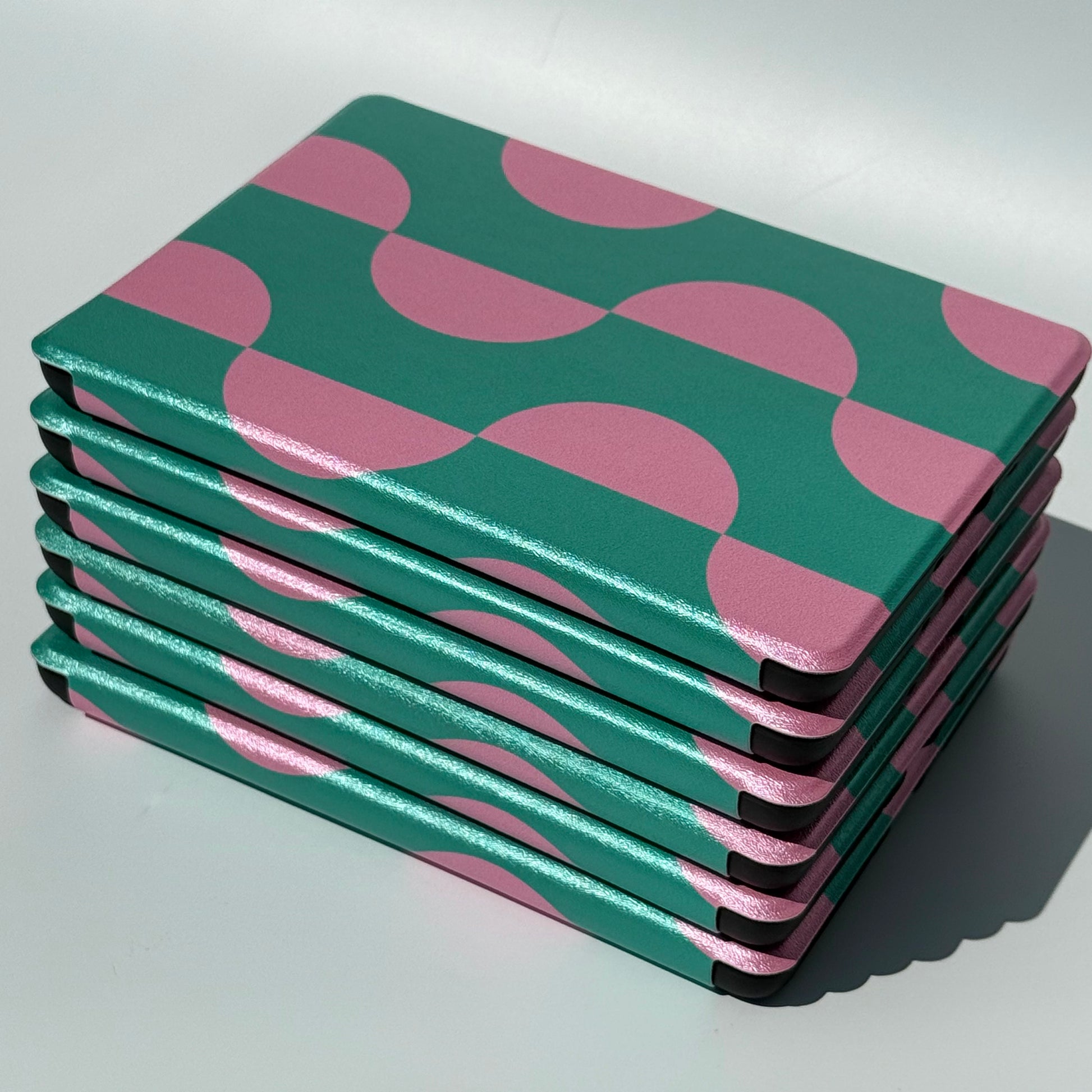 Stack of Case Society Pink Crescent Kindles in green and pink side view