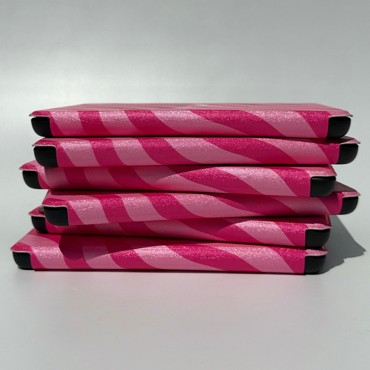 Side stack of Shhh I'm Reading pink wavy stripe Kindle cases