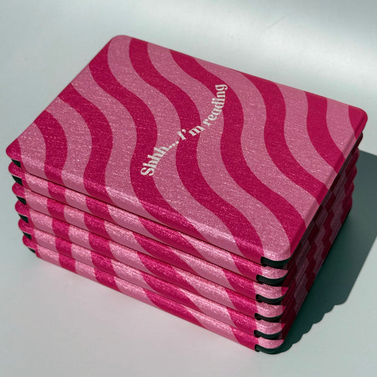 Stack of Shhh I'm Reading pink wavy stripe Kindle cases, top view