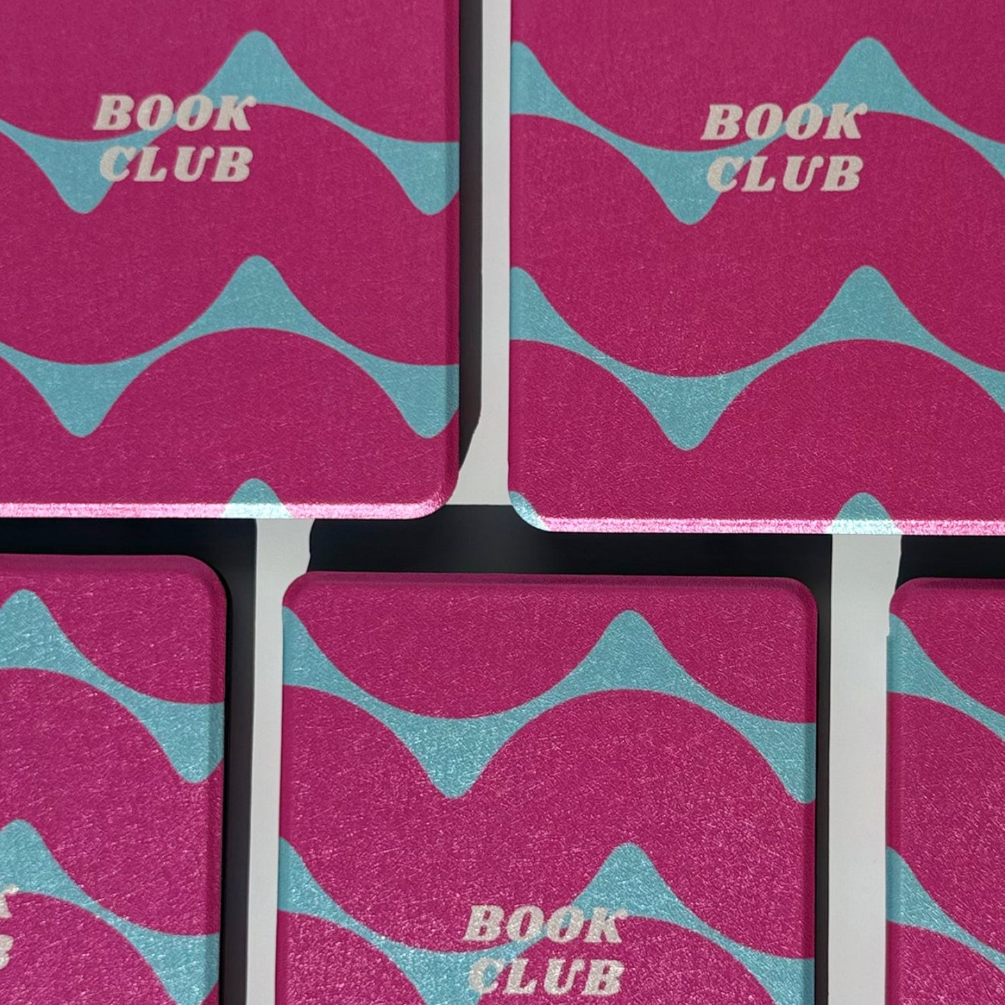 Front pair of Tidal Crush pink and teal wavy Kindle cases with book club print