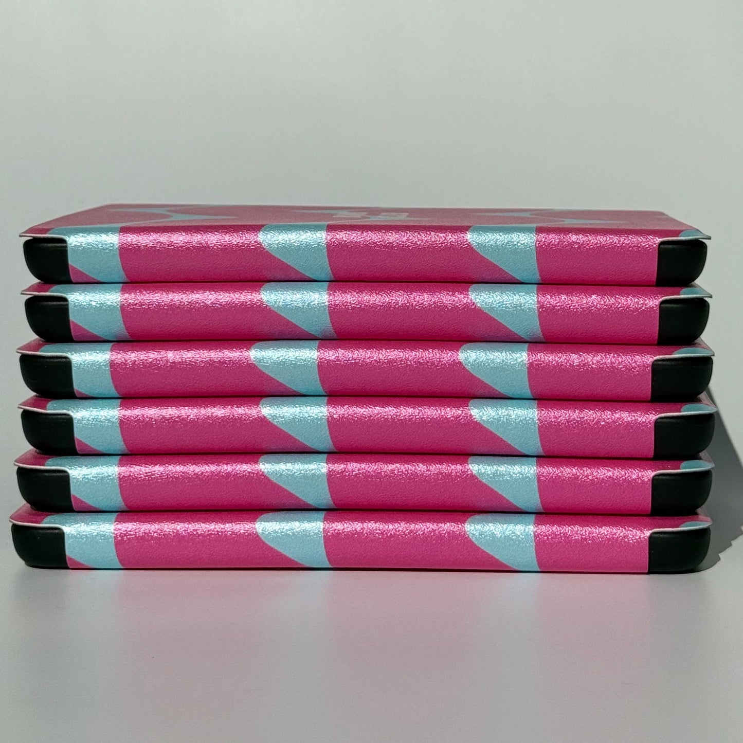 Side stack of Tidal Crush pink wavy Kindle cases showing the slim profile