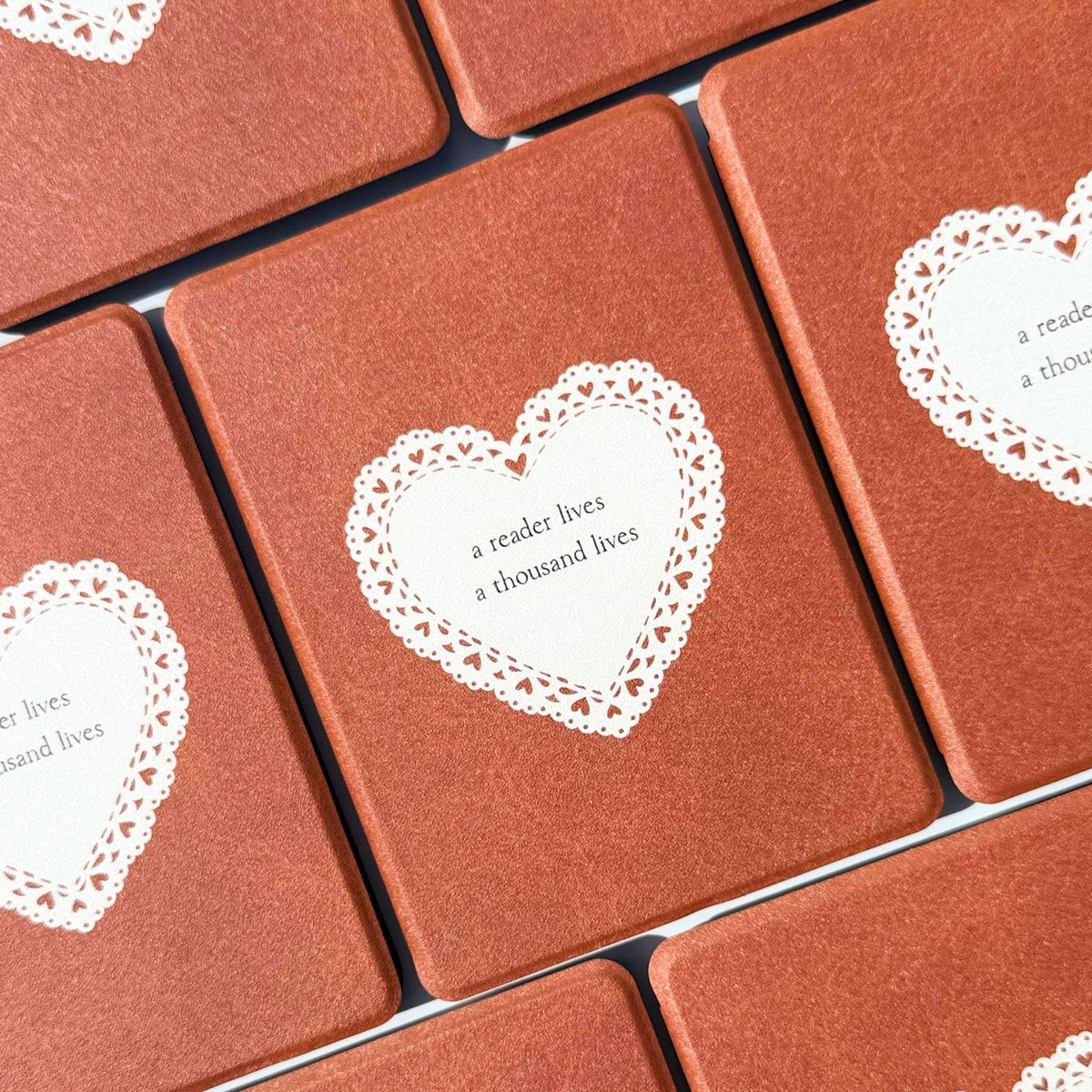 A Thousand Lives Kindle cases laid flat in a grid, warm tan brown with lace hearts, Australia