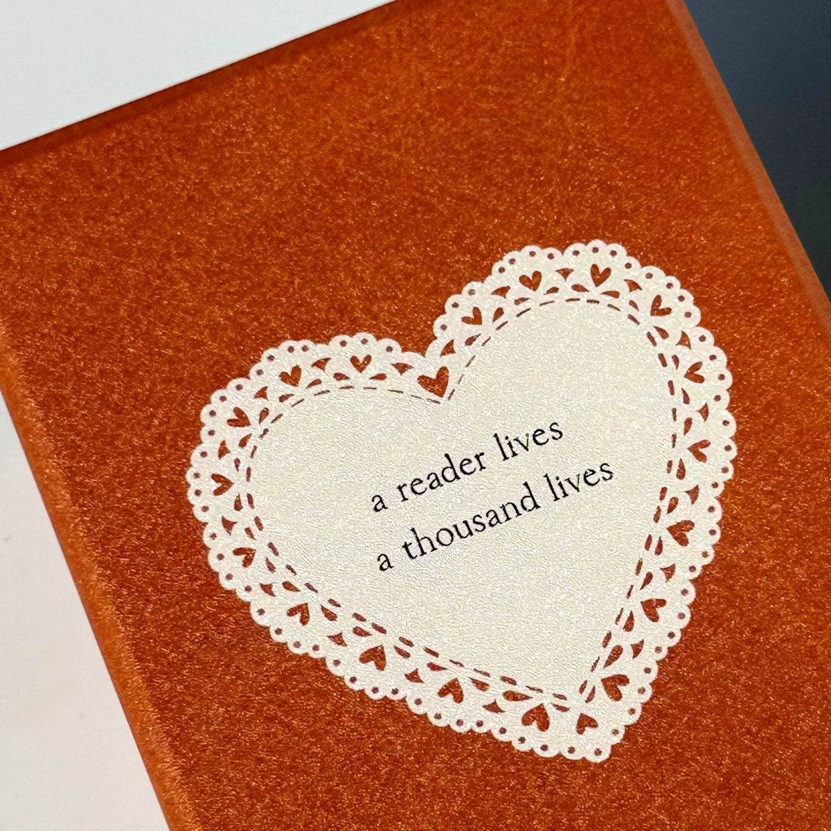 Close-up of the lace heart and bookish quote on the A Thousand Lives Kindle case
