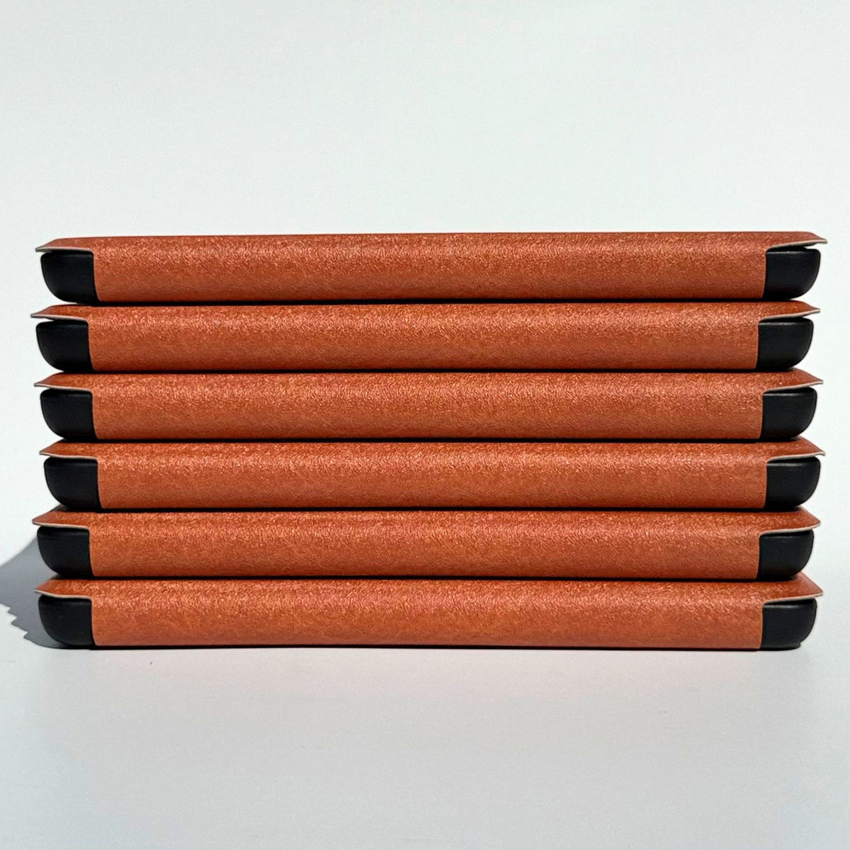 Six tan brown Kindle cases stacked on their sides with soft black corners, Australia
