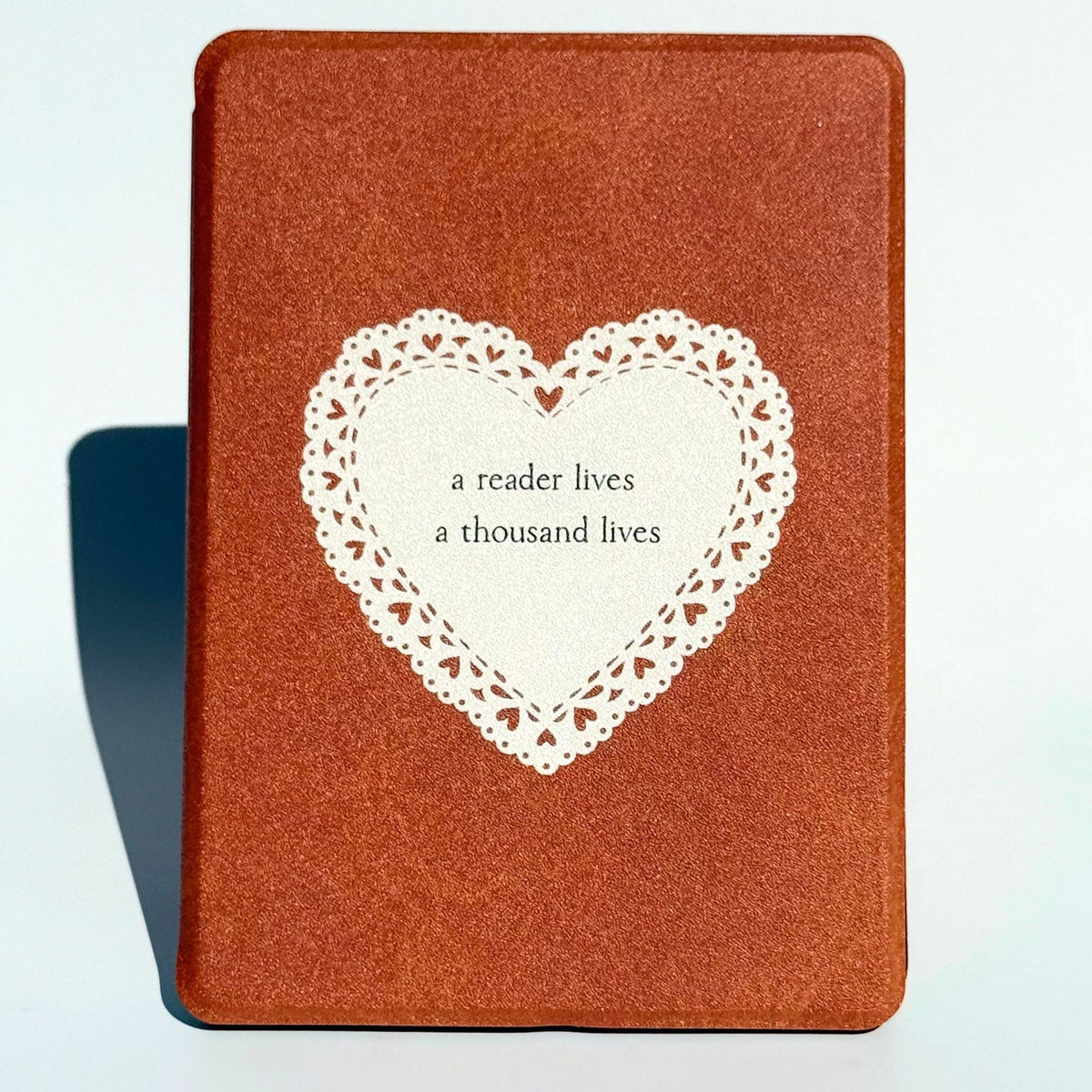 A Thousand Lives Kindle case standing upright in tan brown with a white lace heart, Case Society Co