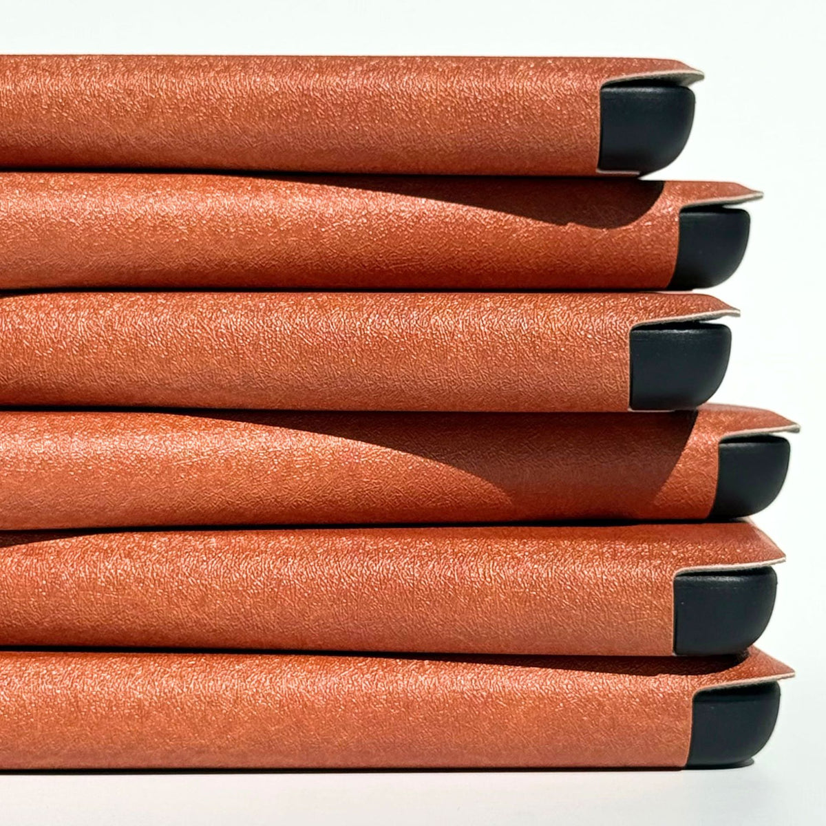 Side view of stacked A Thousand Lives Kindle cases showing the textured tan finish