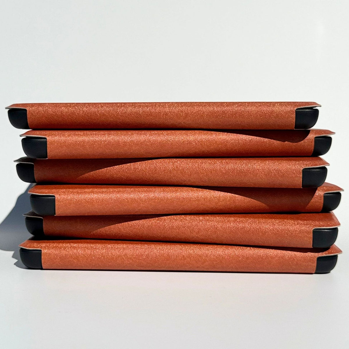 Neat stack of tan brown A Thousand Lives Kindle Colorsoft cases