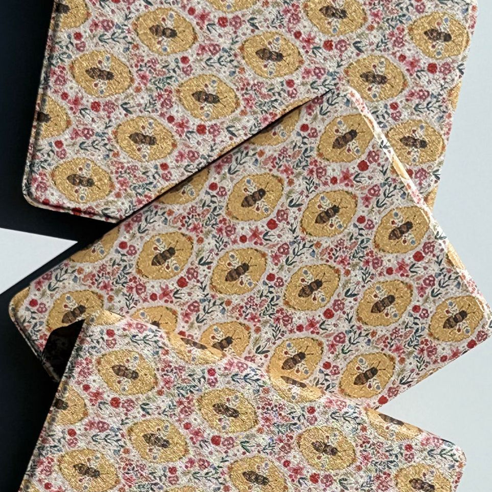 Angled stack of Beekeeper's Garden Kindle cases — cottagecore golden bee and wildflower tapestry print, Case Society AU