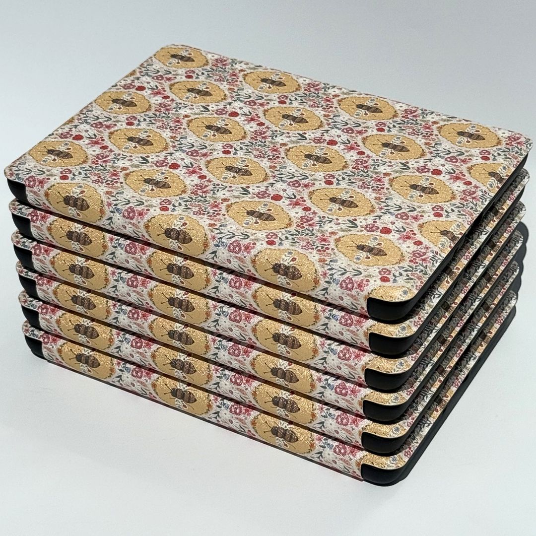 Three Beekeeper's Garden Kindle cases overlapping in a flatlay showing detailed William Morris bee and floral print