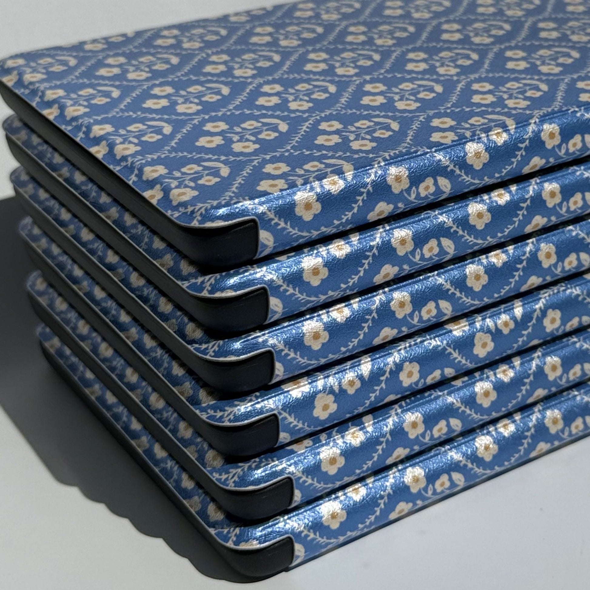 Angled stack of Bluebell blue floral Kindle cases with protective black corners — Case Society