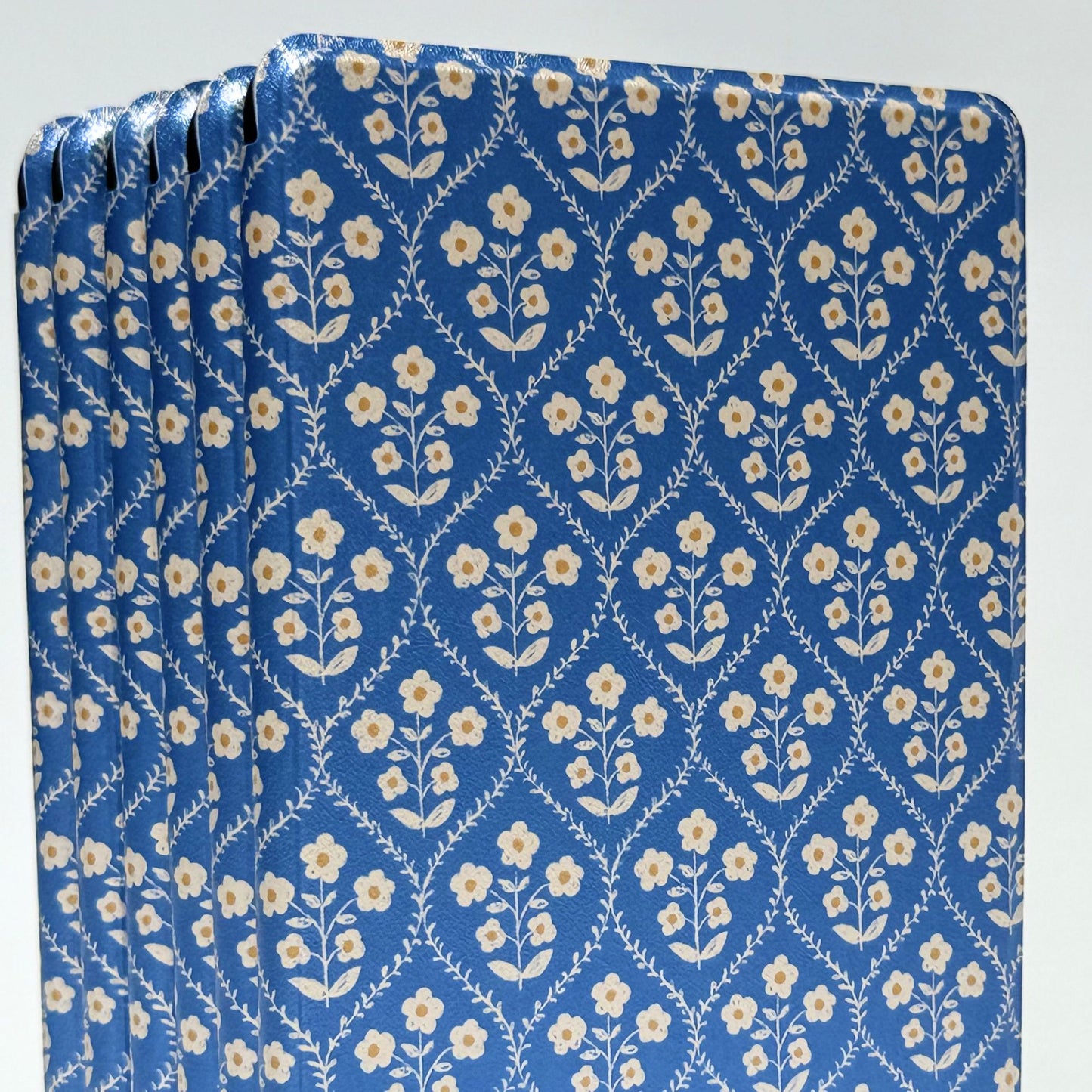 Bluebell Kindle case stack showing the cream floral sprig detail on deep blue, a floral Kindle cover