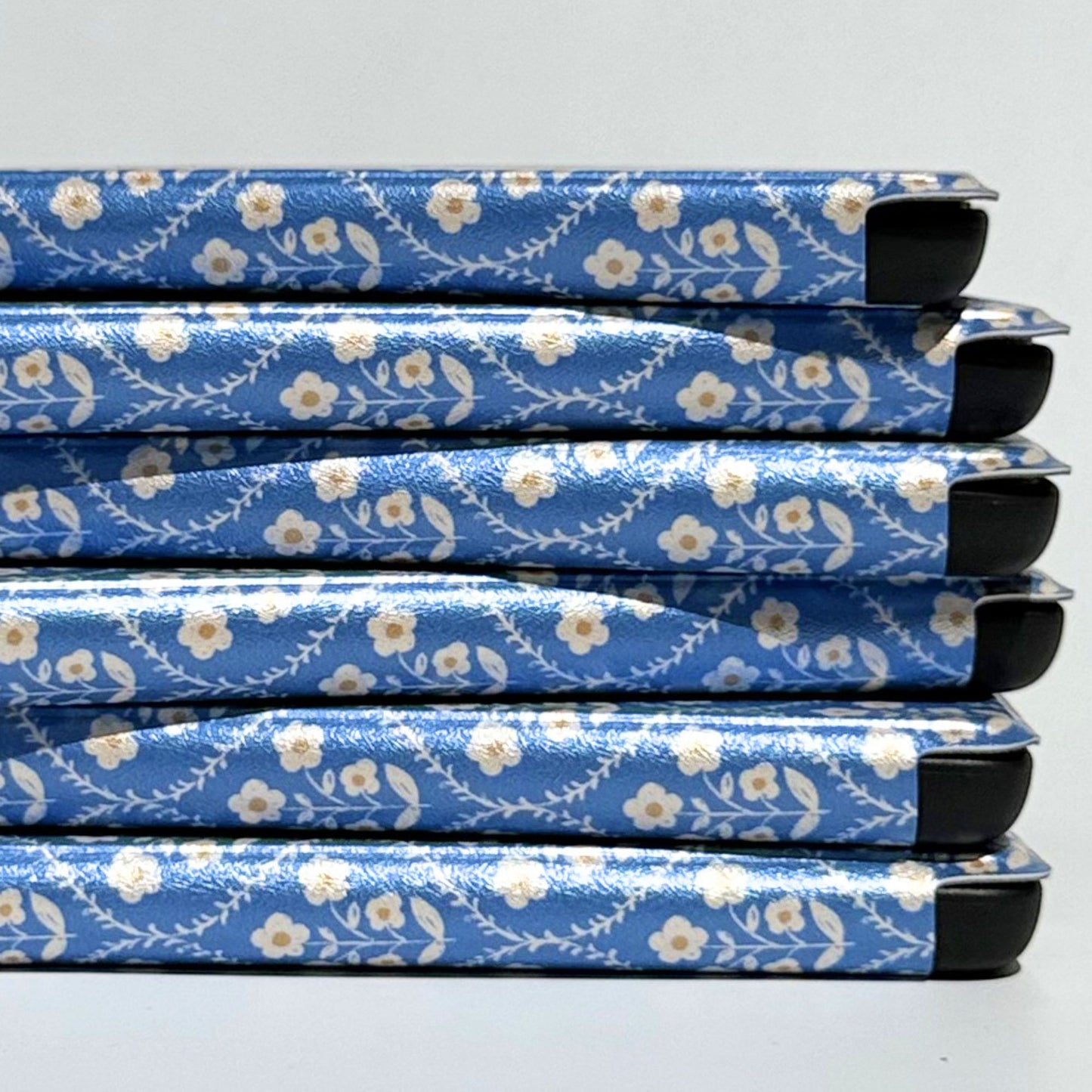 Bluebell Kindle cases stacked at an angle, showing reinforced corners and blue floral cover — Case Society Australia