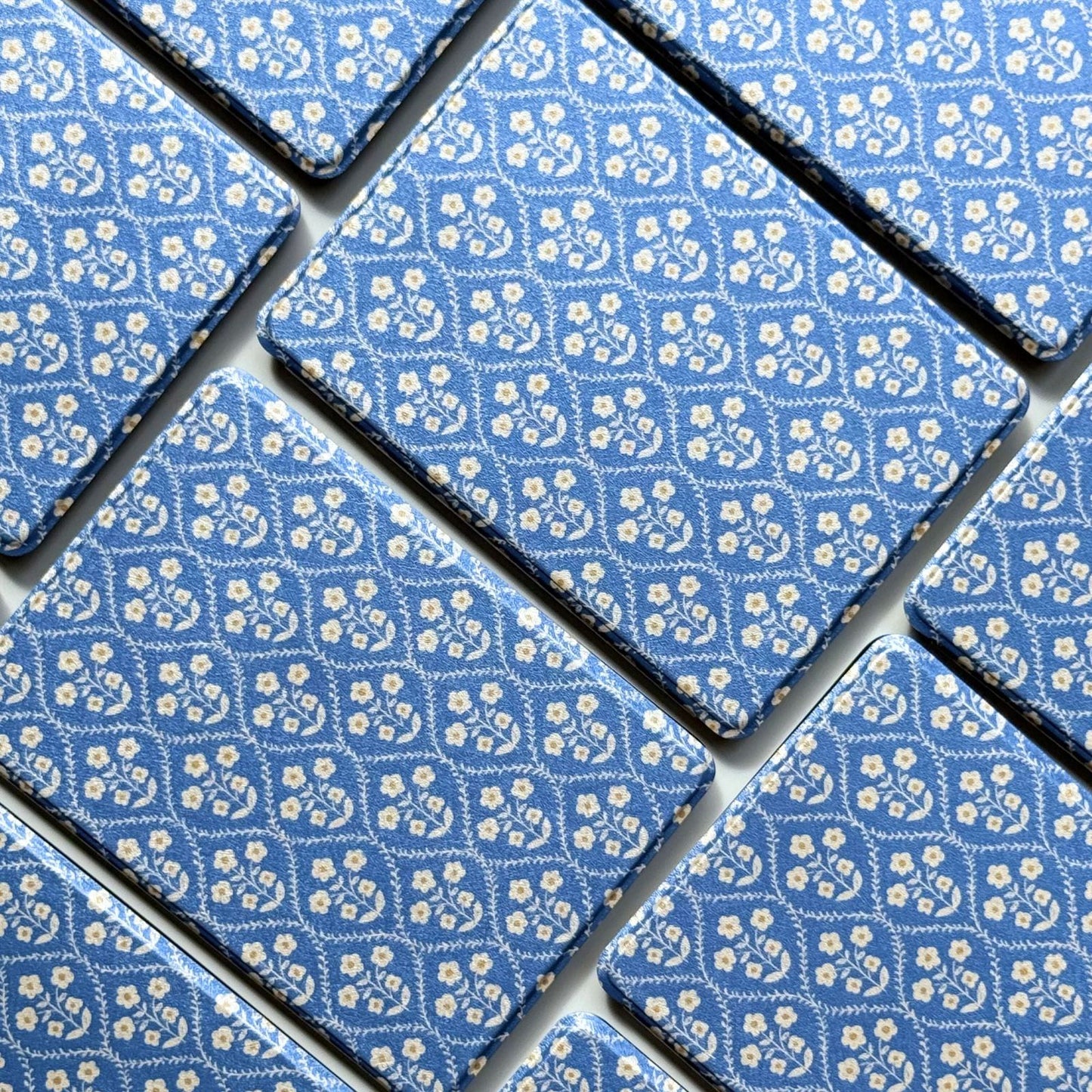 Close-up of the Bluebell Kindle case pattern, small cream flowers on cornflower blue in a vintage lattice print
