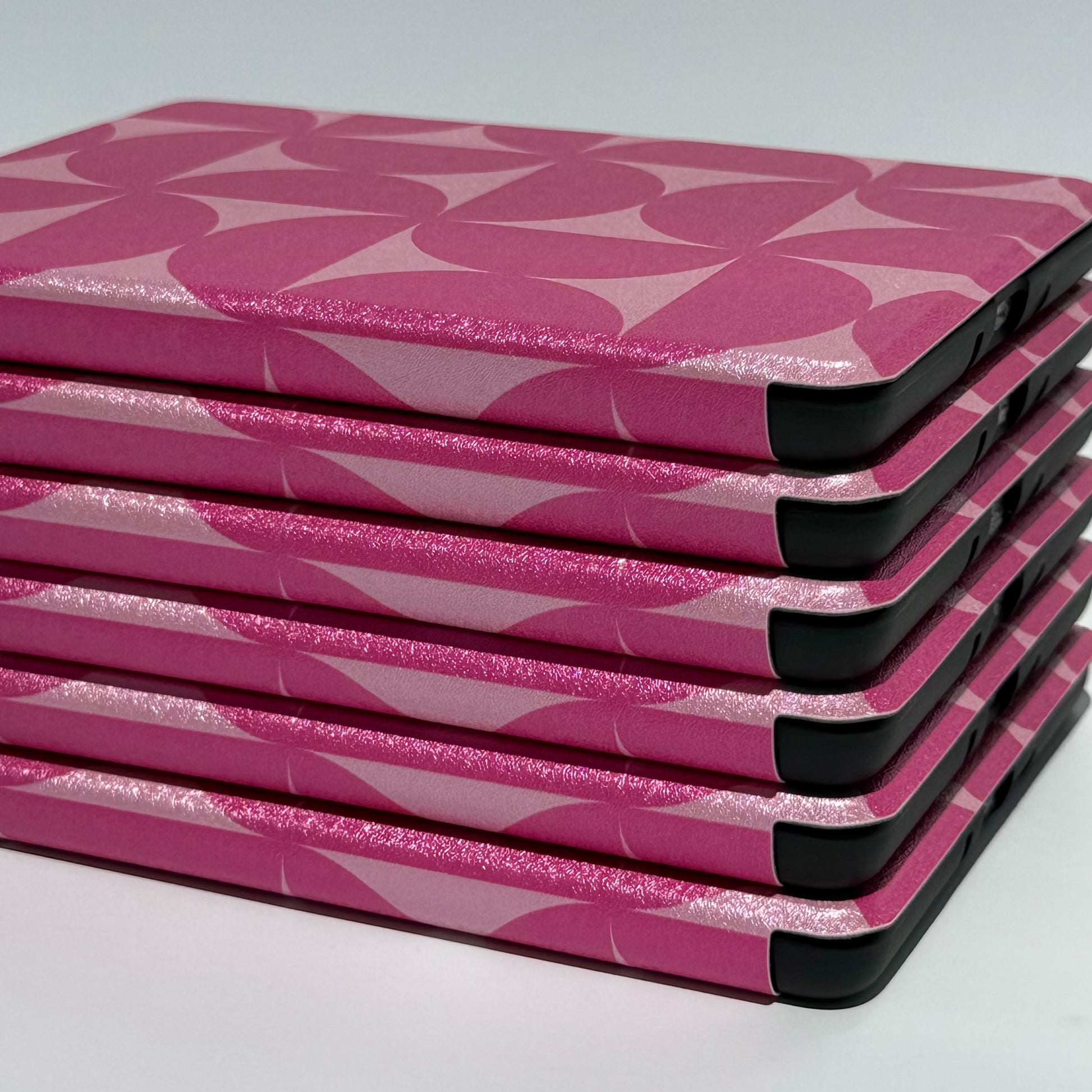 Blushing Moon Kindle Case - close up side view of stack of pink geometric printed cases 