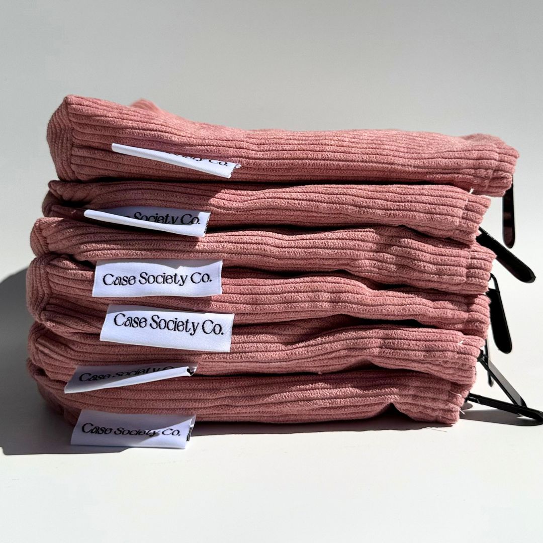 Stack of six folded blush pink corduroy pouches with Case Society Co labels