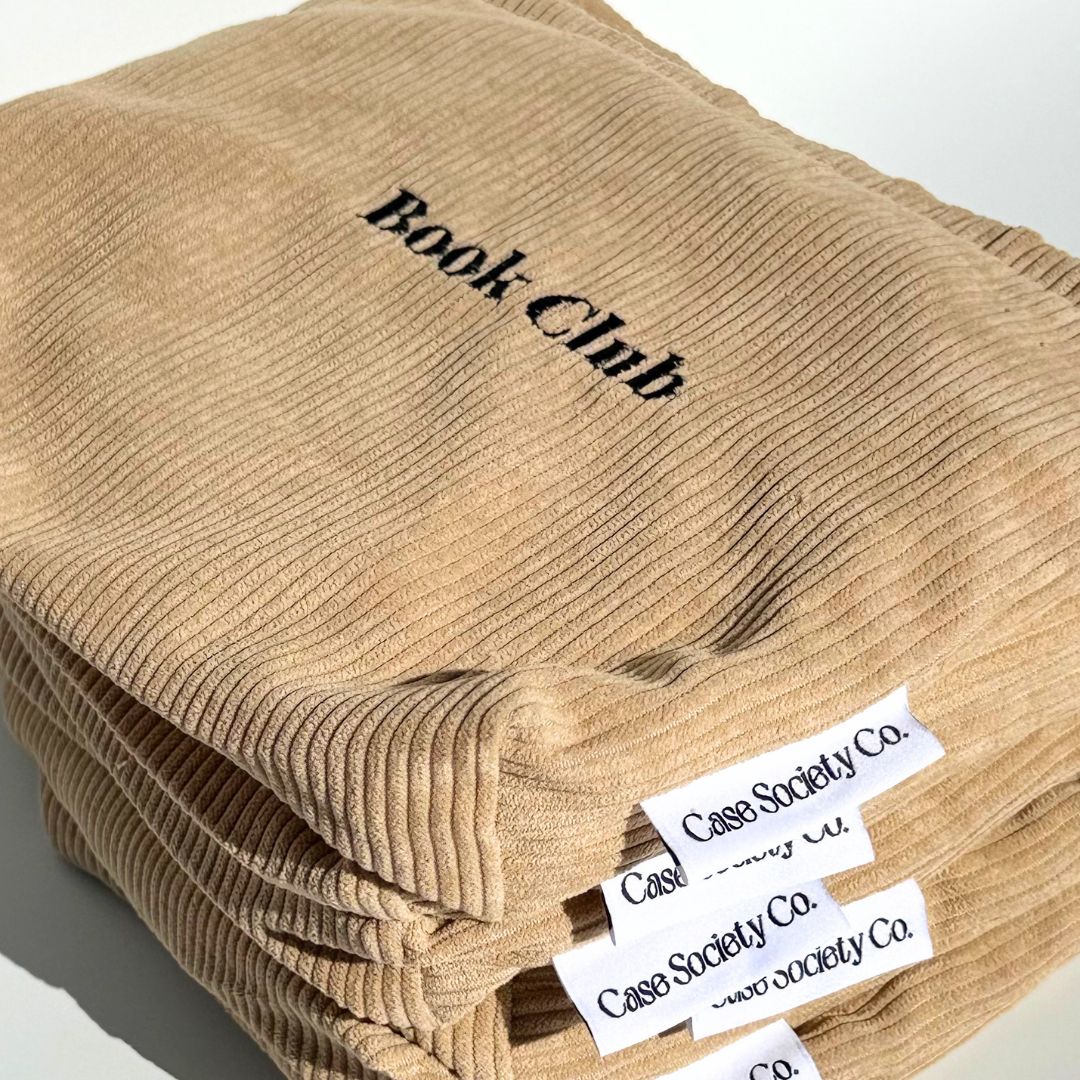 Two honey corduroy e-reader pouches overlapping in afternoon light with Book Club embroidery