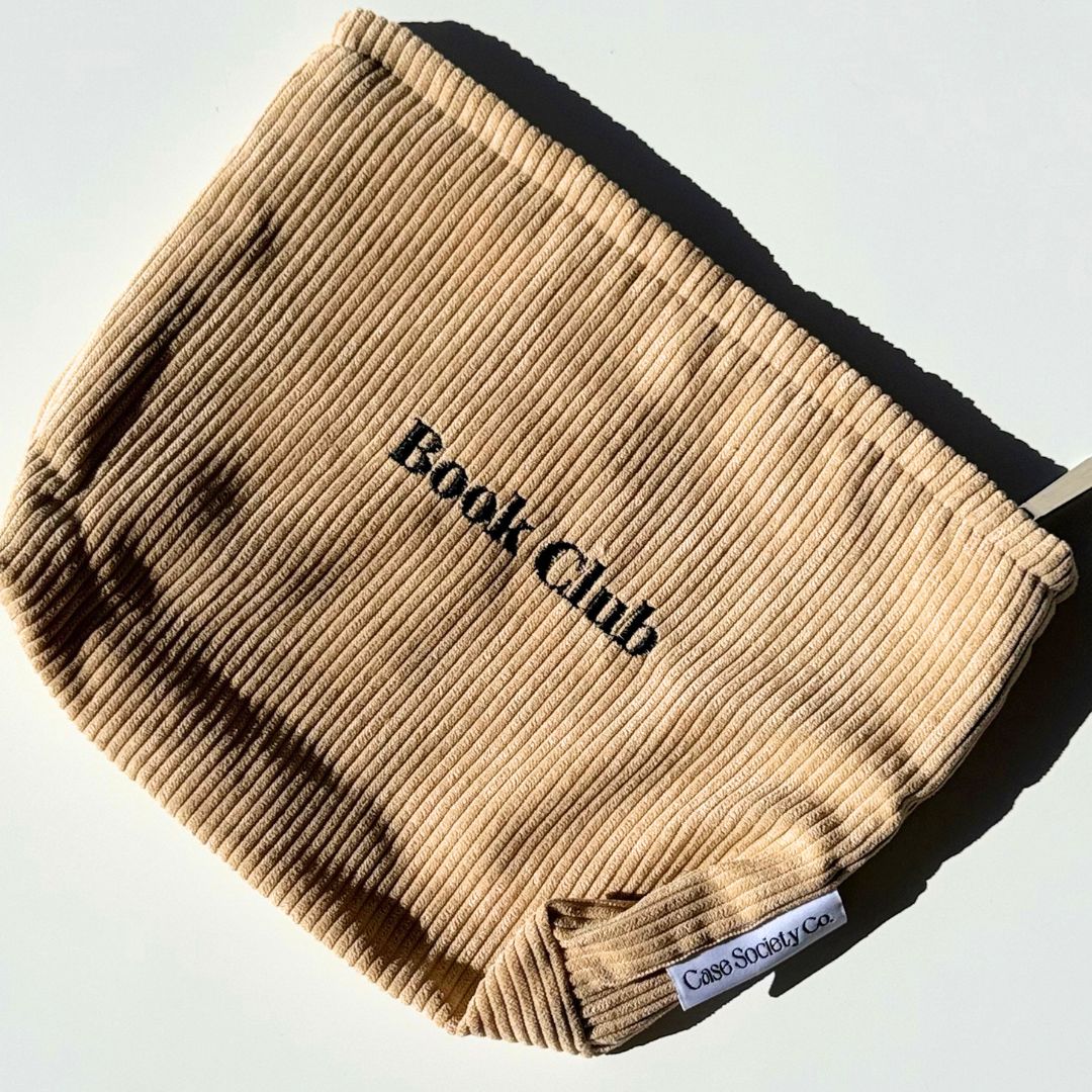 Front of the honey Book Club kindle pouch showing embroidered lettering on soft corduroy