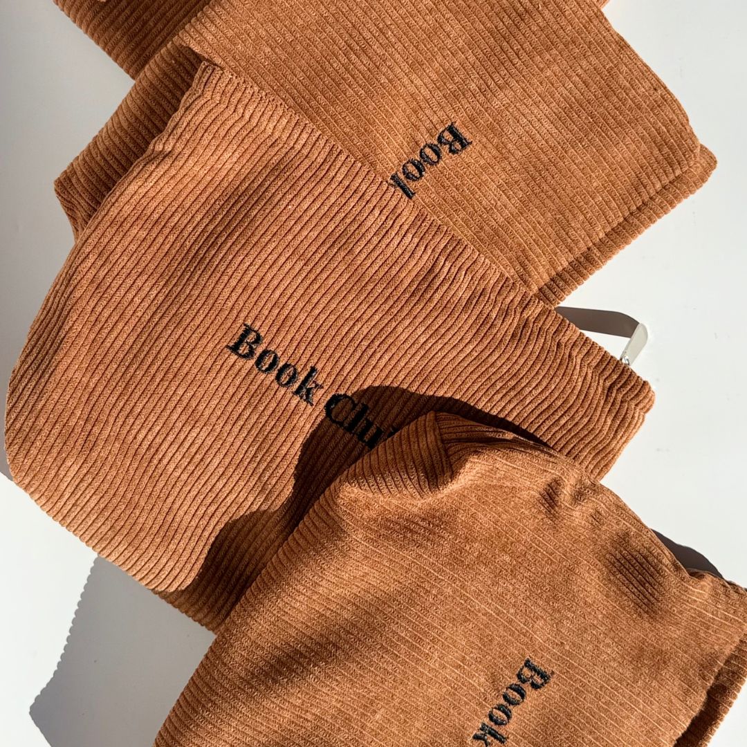 Group of rust brown Book Club book pouches overlapping in afternoon sun