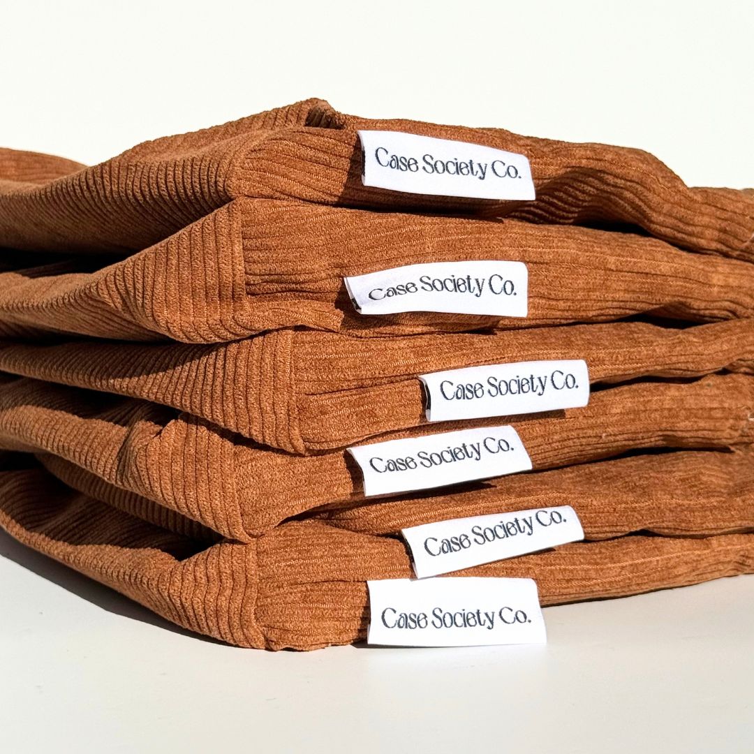 Folded stack of mocha Book Club book sleeves in rust brown corduroy