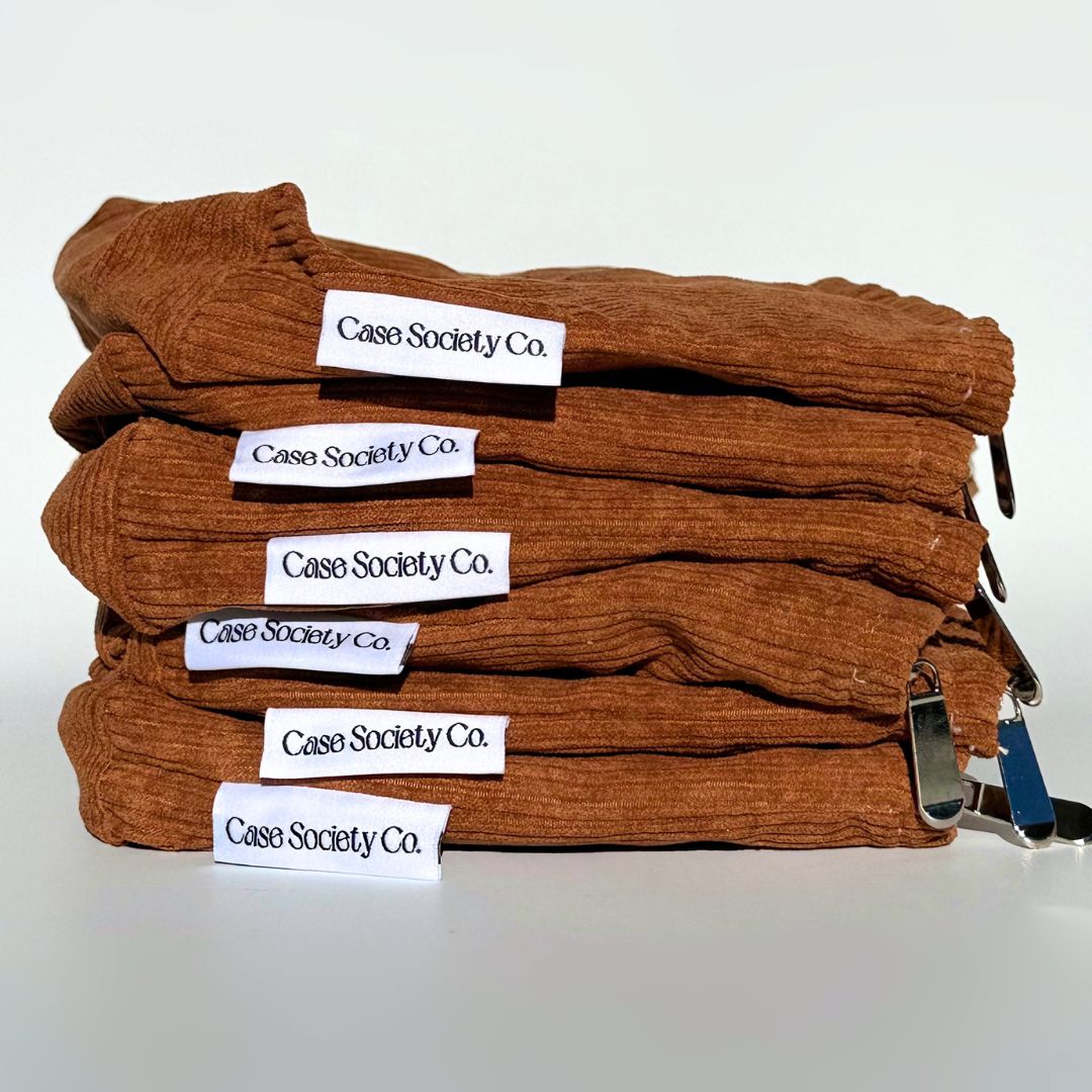 Side stack of six folded mocha corduroy pouches with Case Society Co labels