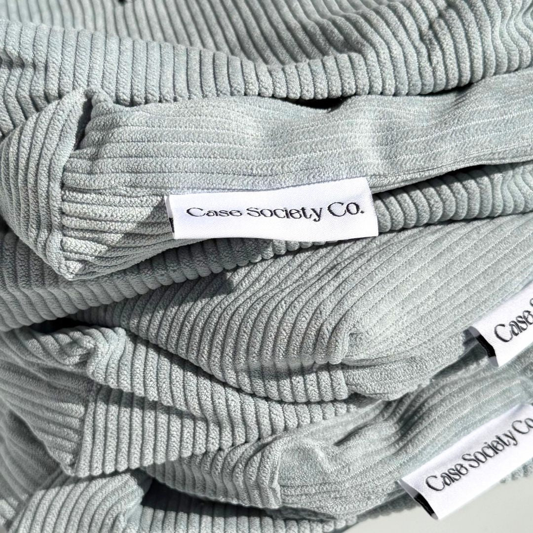 Folded powder blue pouches with woven Case Society Co labels in close detail