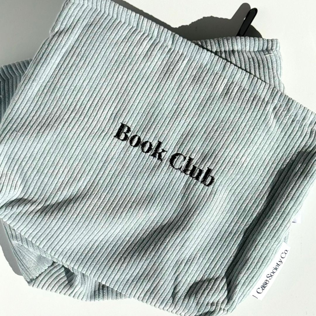 Front of the powder blue Book Club kindle pouch with embroidered lettering on soft corduroy