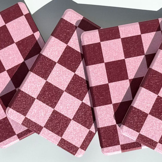 Stack of six Bordeaux Fiction Kindle cases in pink and burgundy checkered design