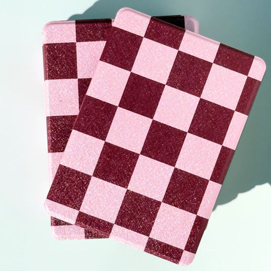Close-up detail of Bordeaux Fiction pink and burgundy checkered Kindle case pattern — premium textured finish