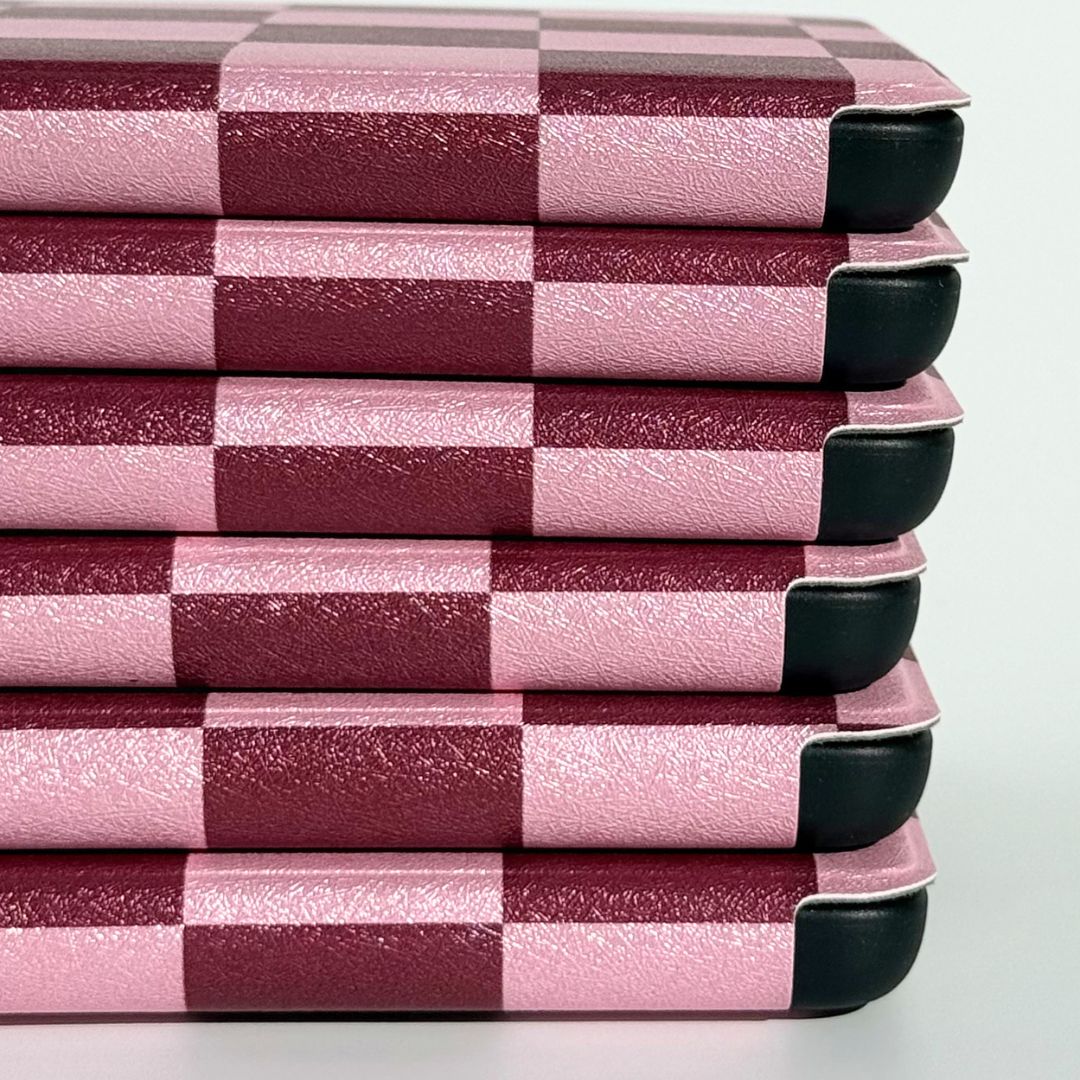 Side view of stacked pink checkered Kindle cases highlighting reinforced protective corners — Bordeaux Fiction