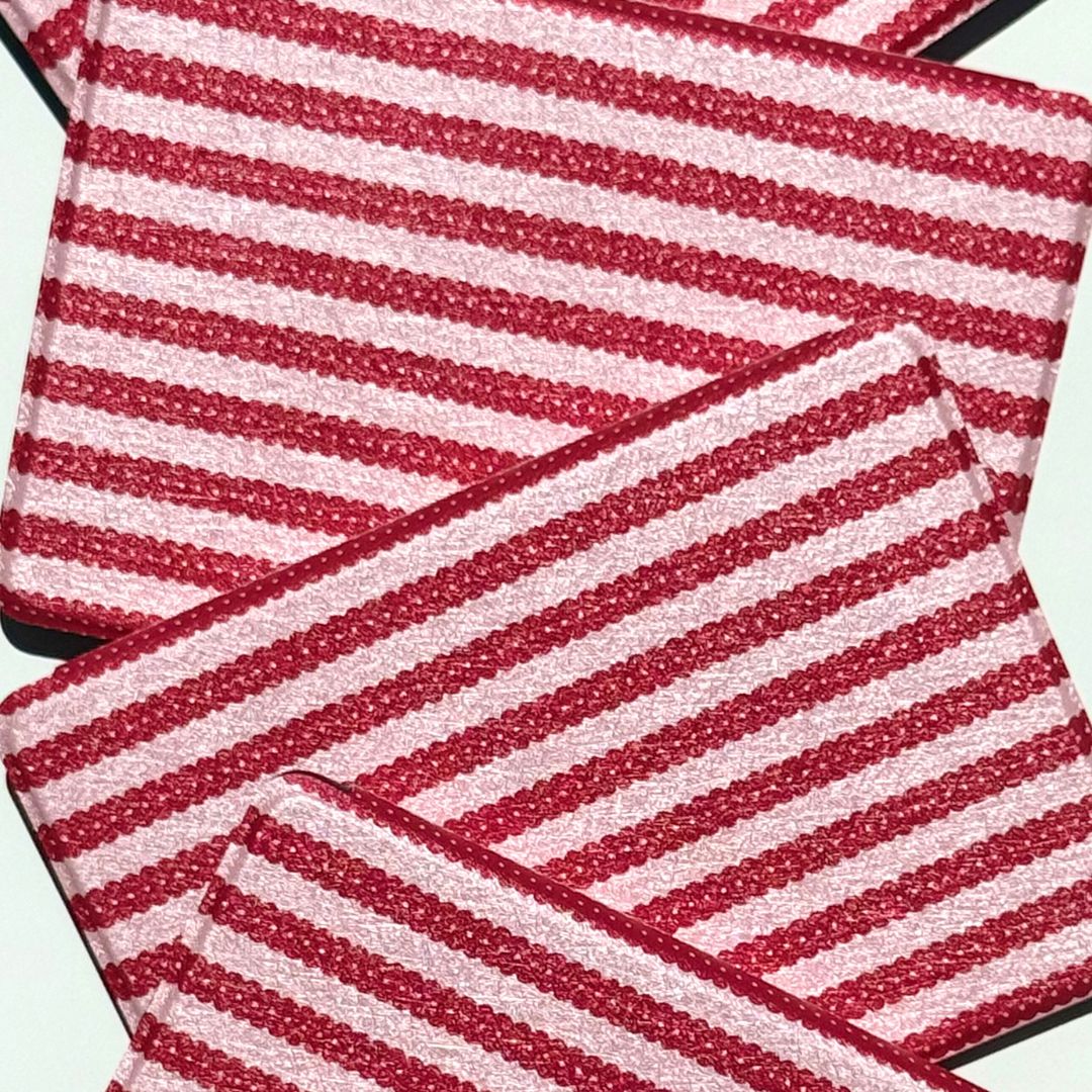 Three Cherry Ledger Kindle cases overlapping in a flat lay, scalloped red stripes on pink.