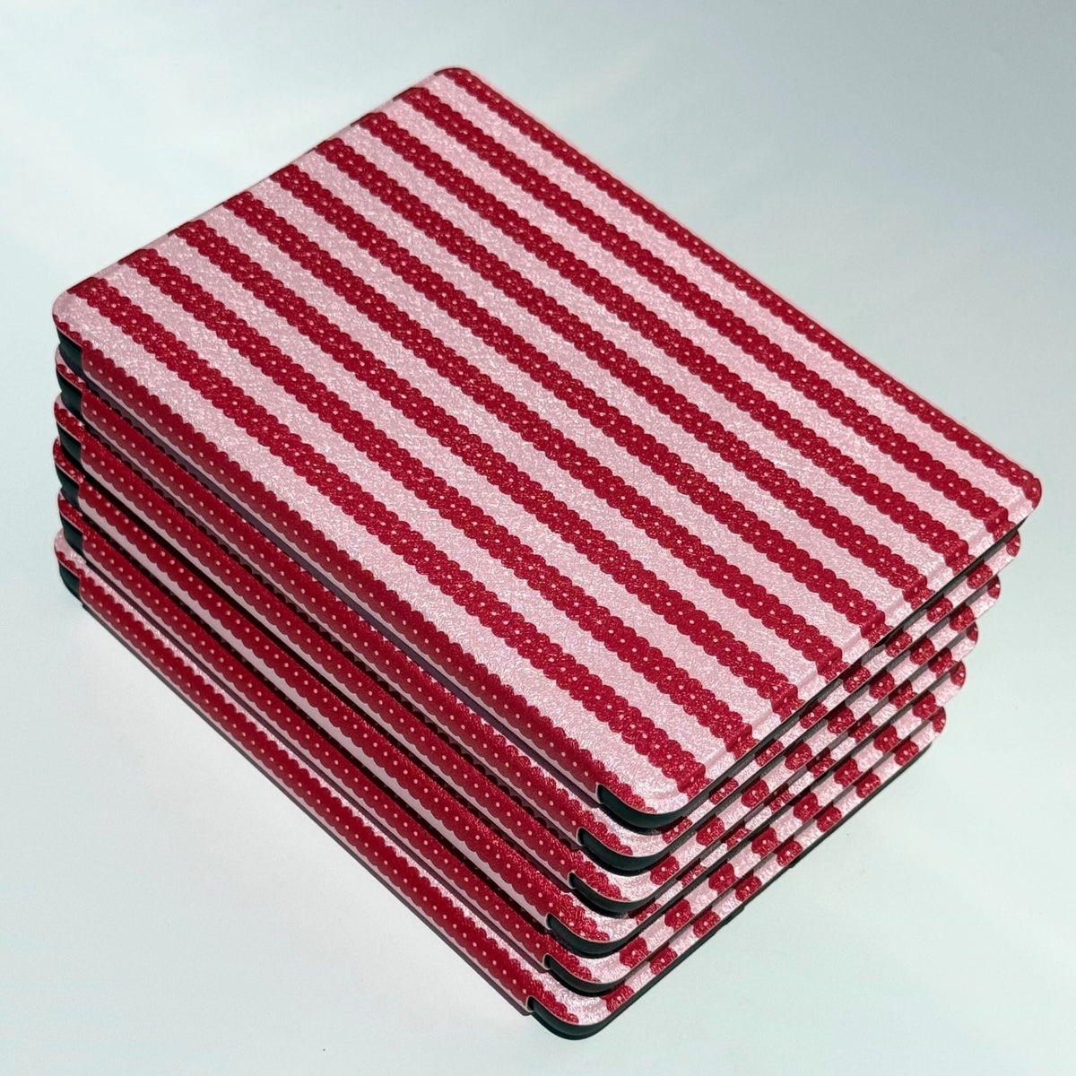 A stack of Cherry Ledger Kindle cases from above, red candy stripes across the top cover