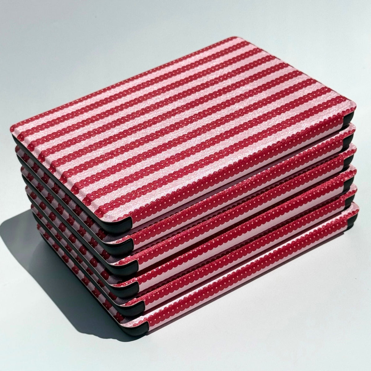 Angled stack of Cherry Ledger cases, cherry red stripes over soft pink, Case Society Co