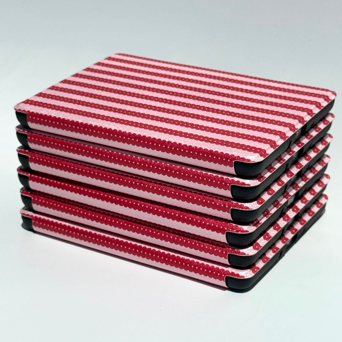 Stacked Cherry Ledger Kindle cases with black corners showing, candy stripe spines