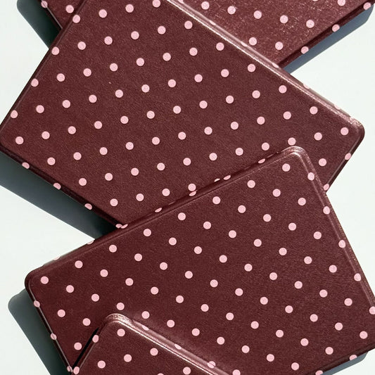 Close-up of overlapping Cocoa Kiss Kindle cases showing the soft pink polka dot print and slim profile
