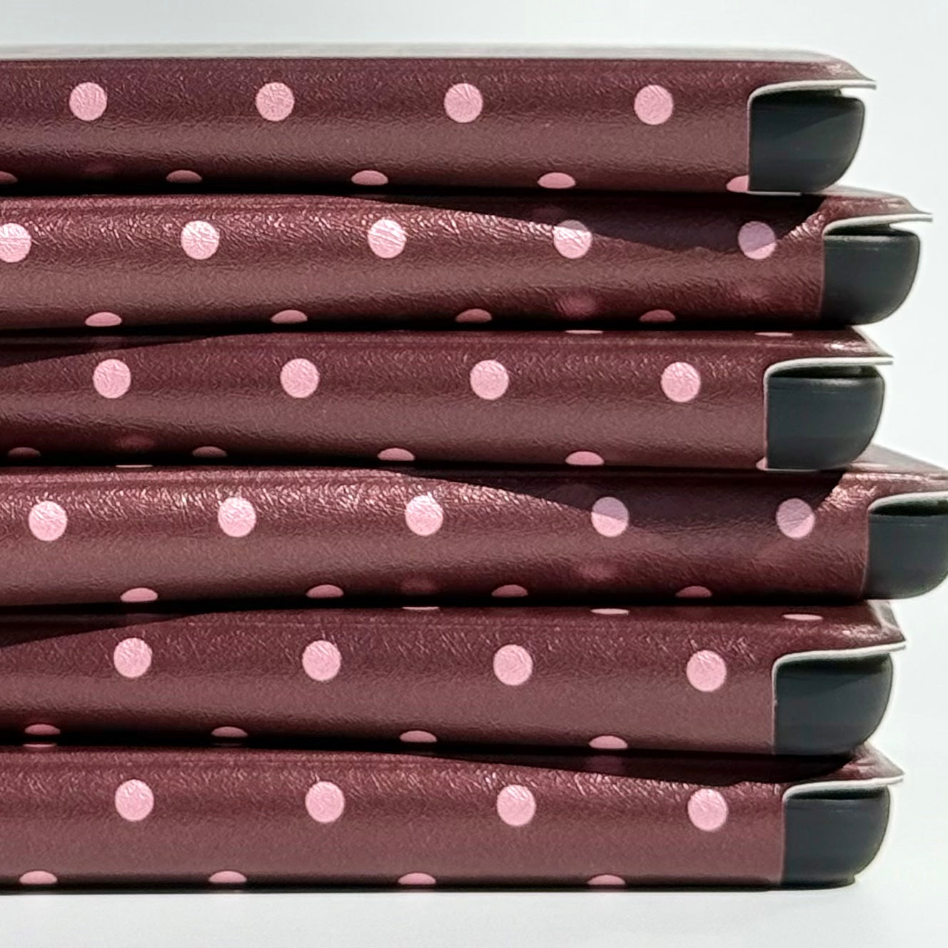 Close up of the blush pink dot spine pattern across a stack of Cocoa Kiss Kindle cases