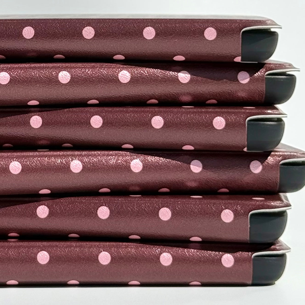 Close up of the blush pink dot spine pattern across a stack of Cocoa Kiss Kindle cases