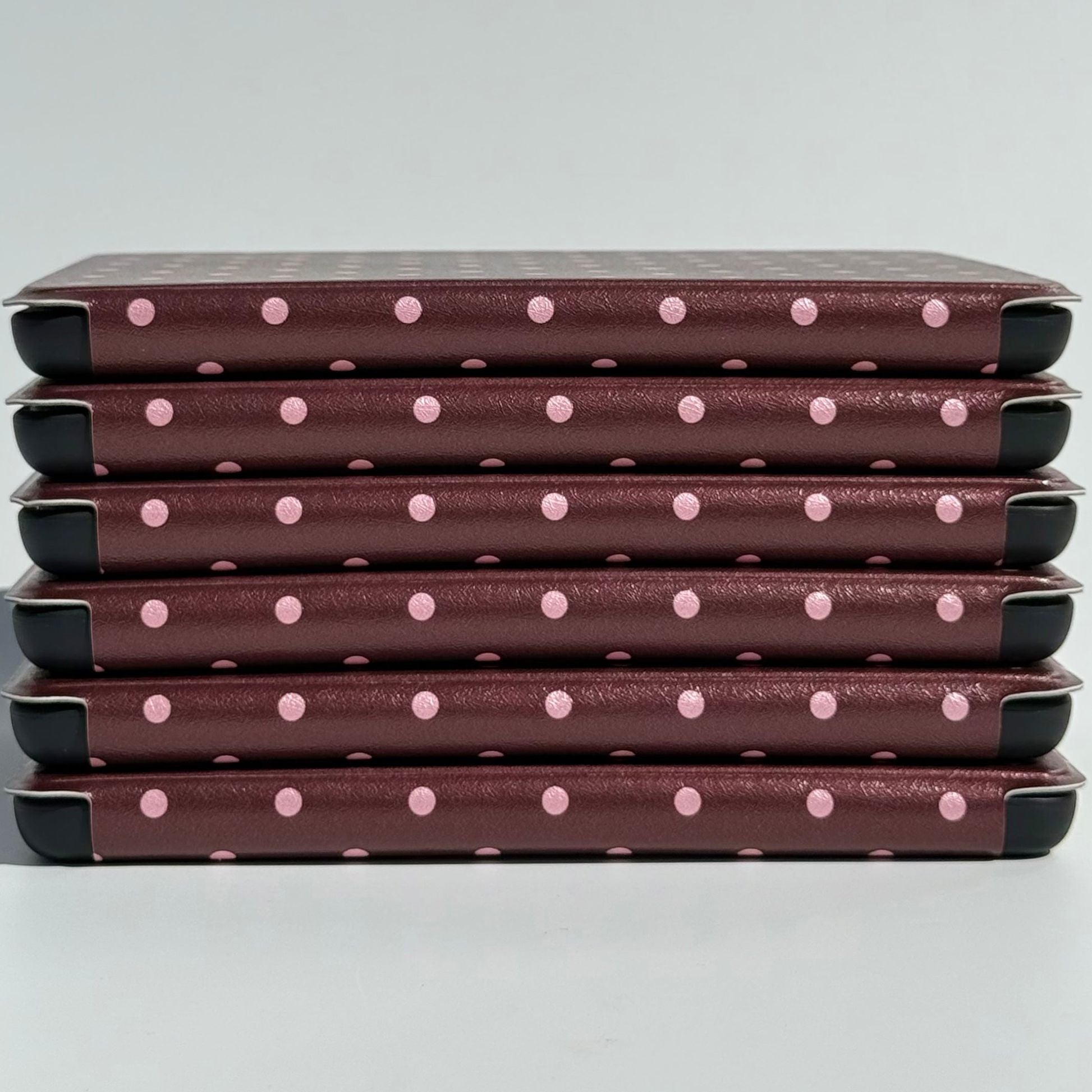 A stack of Cocoa Kiss Kindle cases from Case Society Australia, pink dots along every spine