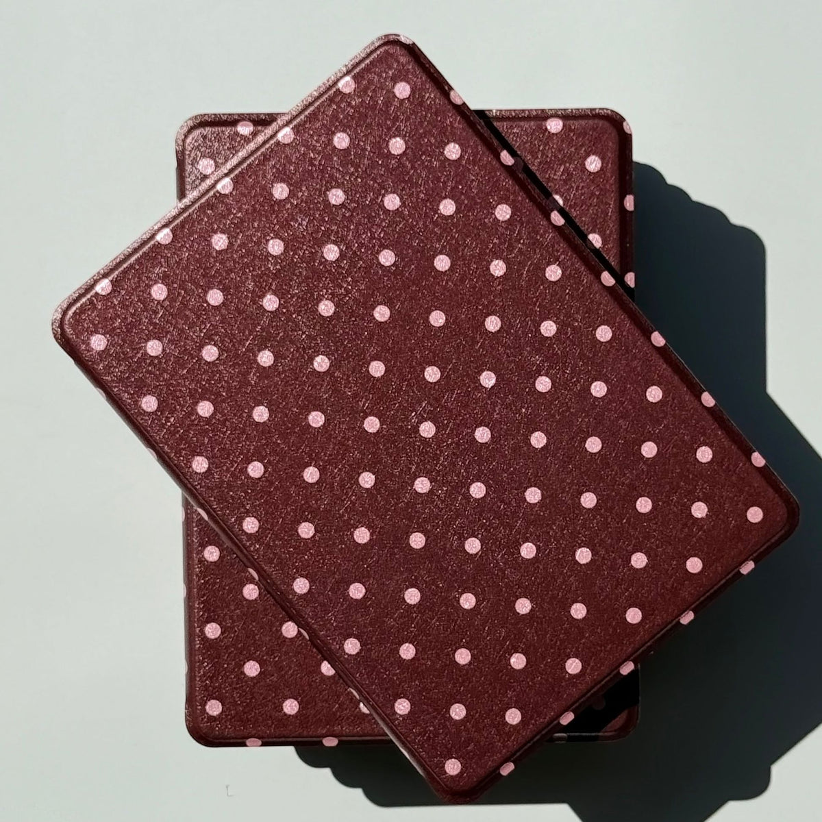 Two Cocoa Kiss Kobo cases stacked in sunlight, brown and pink polka dot covers by Case Society Australia