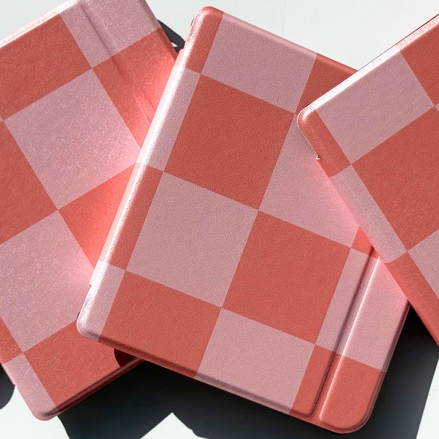 Top angle of stacked Fairy Tales Kobo Libra cases, coral and pink checkerboard cottagecore cover with shockproof bumper